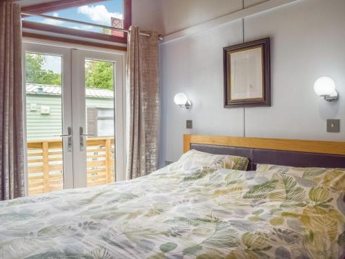 Schlafzimmer mit einem Bett und einem Fenster in der Unterkunft Woodlands Lodge in Colmonell