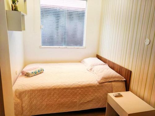 a small bedroom with a bed and a window at Pé na areia do Flamengo in Salvador