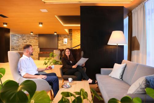 a man and woman sitting in a living room at Wellness Hotel Svornost in Harrachov