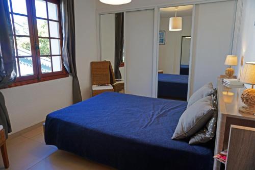 une chambre avec un lit bleu et un miroir dans l'établissement Villa les Voiliers 3, bel appartement 4 personnes face plage, à Saint-Georges-de-Didonne