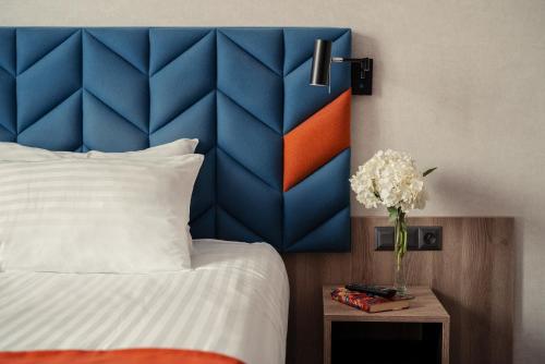 Hotel Faros Gdansk Airport في غدانسك - ريبييخو: غرفة نوم مع اللوح الأمامي الأزرق والبرتقالي وسرير