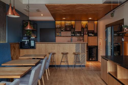 a bar in a restaurant with wooden tables and chairs at Hotel Faros Gdansk Airport in Gdańsk-Rębiechowo