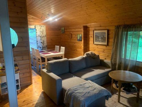 ein Wohnzimmer mit einem Sofa und einem Tisch in der Unterkunft Rauhallinen mökki luonnon keskellä. in Orivesi