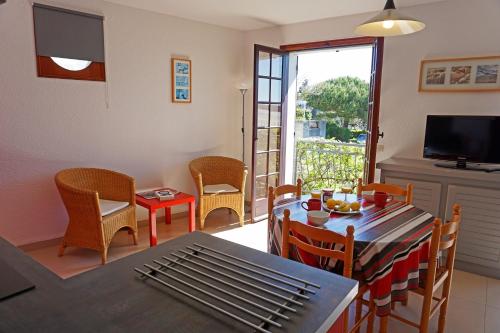 un salon avec une table, des chaises et une télévision dans l'établissement Villa les Voiliers 3, bel appartement 4 personnes face plage, à Saint-Georges-de-Didonne