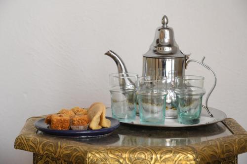 a table with a tea kettle and glasses on it at Riad Berenssi in Marrakech