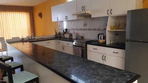 a kitchen with white cabinets and a black counter top at ArenaNorte in Pimentel