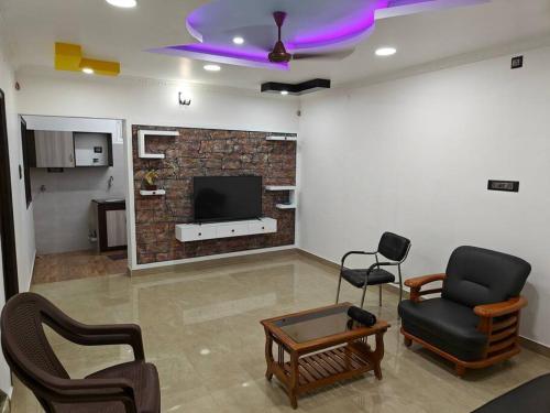 a living room with two chairs and a tv at Treva Pent House in Karaikal
