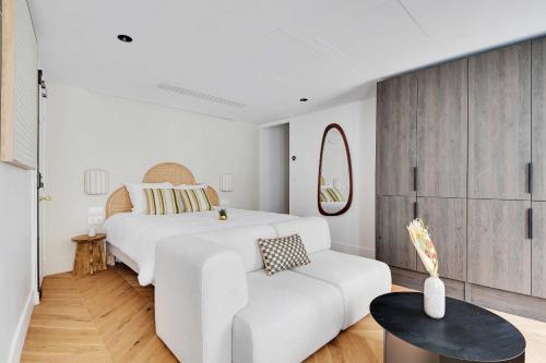 een witte slaapkamer met een wit bed en een witte bank bij Brand New Modern Studio in Central Paris - 2P - B1 in Parijs