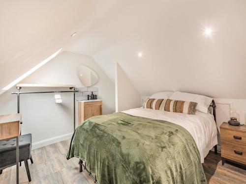 a white bedroom with a bed and a chair at Ysgubor Caemai in Bangor-is-y-coed
