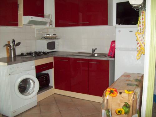 - une cuisine avec des placards rouges et un lave-linge dans l'établissement La Corse mer turquoise et sable fin, à Poggio-Mezzana