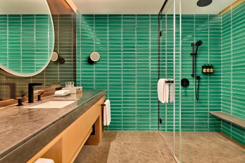 a bathroom with a sink and a shower with blue tiles at Artyzen Habitat Suzhou in Suzhou