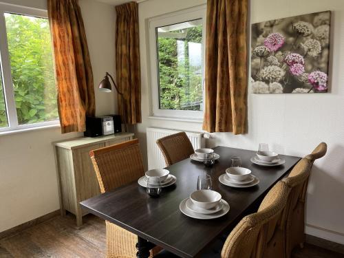 a dining room with a table and chairs and two windows at RBR 782 - Beach Resort Kamperland in Kamperland