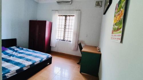 sypialnia z łóżkiem, biurkiem i oknem w obiekcie Nhà Nghỉ Kim Sơn w mieście Hue