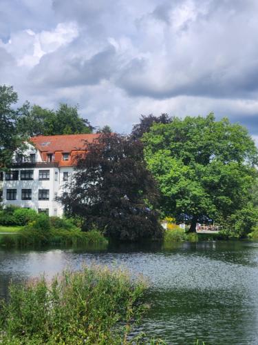 ein Gebäude an der Seite eines Sees mit Bäumen in der Unterkunft Hotel Haus am See in Bad Salzuflen