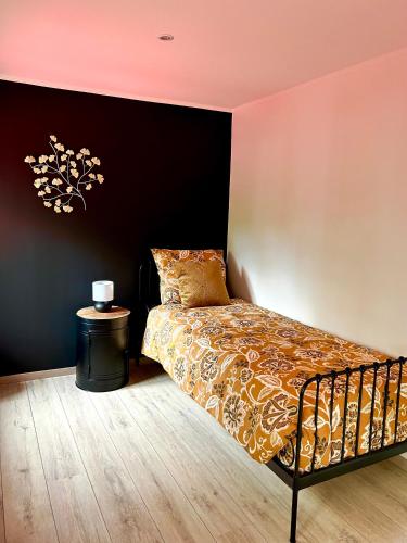 1 dormitorio con cama y pared negra en Les Chambres T4, en Huy