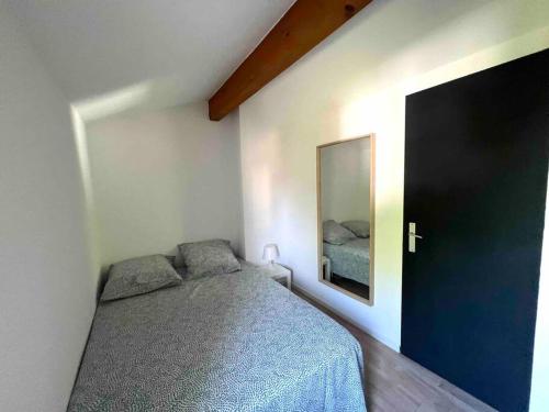 une chambre avec un lit et un miroir au mur dans l'établissement Idéal pour vos vacances, à Saint-Laurent-dʼAigouze