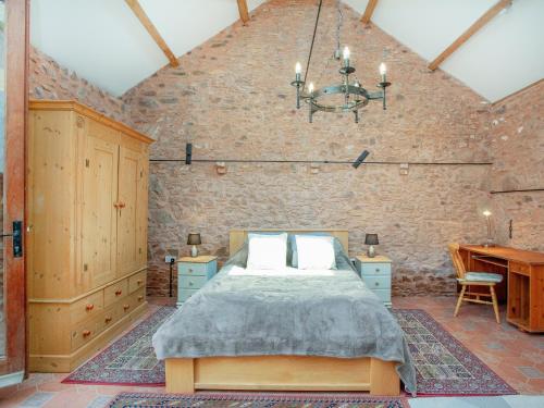 a bedroom with a bed in a brick wall at Parish Land Barn in Spaxton
