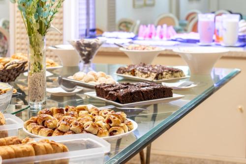 a buffet of pastries and desserts on a glass table at Lancaster Hotel by Castelo Itaipava in Curitiba