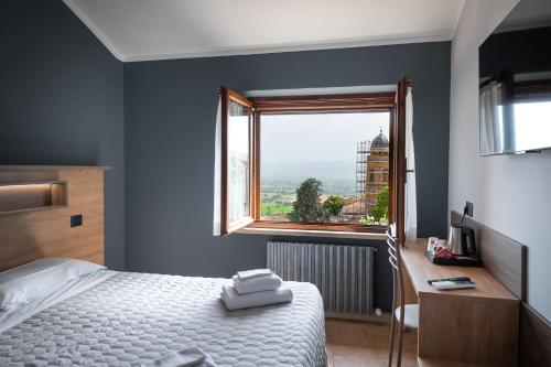 a bedroom with a bed and a window and a desk at Roof Garden Rooms in Assisi