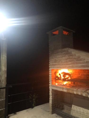 a brick fireplace with a fire in it at night at DARMI in Villa Serrana