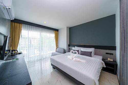 a bedroom with a large bed with a large window at LHC HOTEL AND RESORT in Pattaya Central