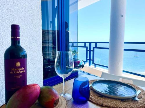 una bottiglia di vino e un bicchiere su un tavolo di Stunning sunset ocean view apt. a Taurito