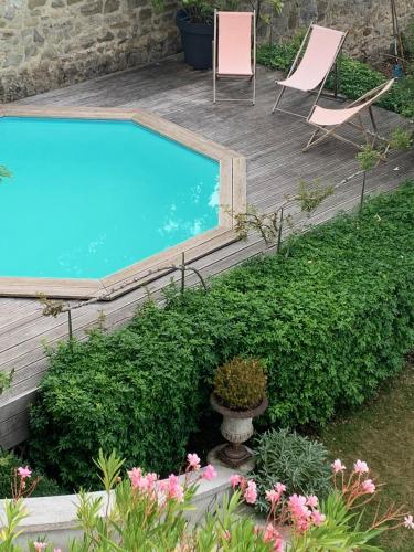 - une piscine dans un jardin avec 2 chaises et des fleurs dans l'établissement MAISON 1903 FONTAINEBLEAU, 70kms de PARIS, à Fontainebleau