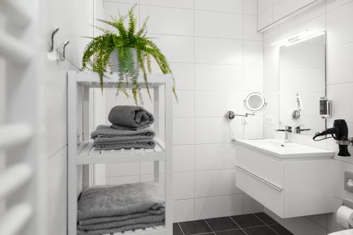 a white bathroom with a sink and a plant on a shelf at SERVENTO Boardinghouse in Erlangen