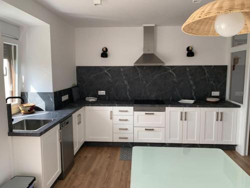 een keuken met witte kasten en een zwart aanrecht bij A de Féliz Ribadeo in Ribadeo