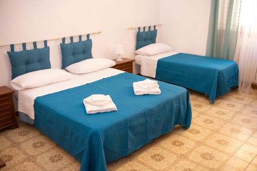 duas camas num quarto com lençóis azuis e toalhas em Casa vacanza “La Maison de famille” em Surbo