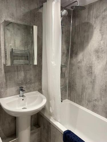 uma casa de banho com um lavatório, um espelho e um chuveiro em The flat at the crooked house em Ulverston