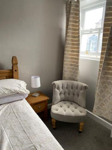 a bedroom with a bed and a chair next to a window at The flat at the crooked house in Ulverston