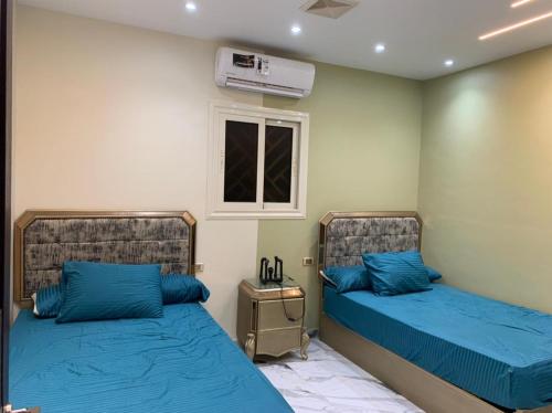 sypialnia z 2 łóżkami z niebieską pościelą i oknem w obiekcie شقه فندقيه الترا لوكس w mieście Asjut