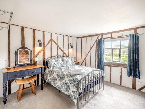 1 dormitorio con cama, escritorio y ventana en Meadowland, en Thornham Magna