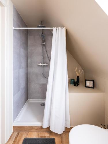 a bathroom with a shower with a white shower curtain at Séjour14 -- Gastenverblijf - volledige 1e verdiep in Veurne