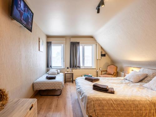 Cette chambre comprend deux lits, un canapé et une télévision. dans l'établissement Séjour14 -- Gastenverblijf - volledige 1e verdiep, à Furnes