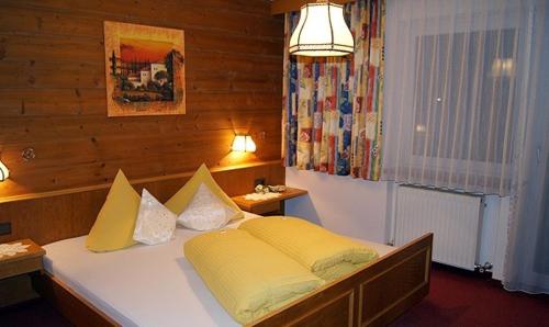 a bedroom with a large bed with yellow pillows at Sport Garni Kapplerhof – Ischgl/Kappl in Kappl