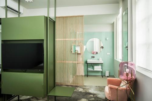 a bathroom with a green cabinet with a television at Clarance Hotel Lille in Lille
