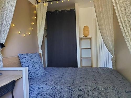 Schlafzimmer mit einem Bett mit blauer Tagesdecke in der Unterkunft La Grelauderie 2 in Saintes