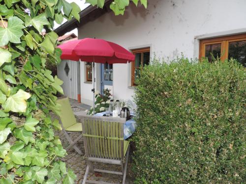 a table with a red umbrella in a garden at Ferienwohnung-Geltendorf Nähe Ammersee in Geltendorf