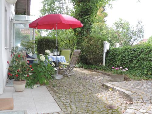 a patio with a table with a red umbrella at Ferienwohnung-Geltendorf Nähe Ammersee in Geltendorf