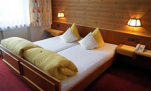 a large bed in a room with two lights at Sport Garni Kapplerhof – Ischgl/Kappl in Kappl