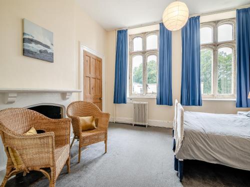 a bedroom with blue curtains and a bed and chairs at Hooke Court in Hooke
