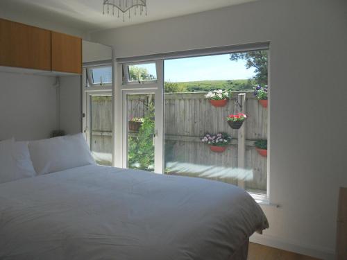 - une chambre avec un lit et une fenêtre ornée de plantes en pot dans l'établissement Chalet One, à West Bay