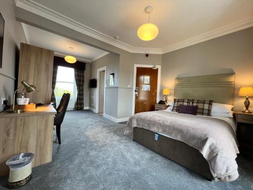 a bedroom with a bed and a desk and a kitchen at Cove Bay Hotel in Aberdeen