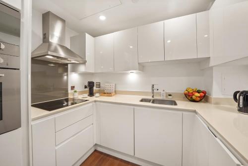 a white kitchen with white cabinets and a sink at Luxury 1 bed flat, minutes from Canary Wharf and South Quay Station in London