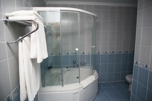 a bathroom with a shower and a tub with towels at West Davraz Hotel in Cobanisa