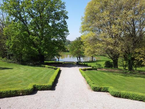 a walkway through a park with a lake and trees at Relais Villa Zaccaria in Bordolano