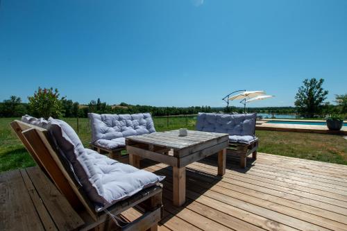 a wooden deck with a table and chairs and a pool at La Villa face au Lac in Saramon