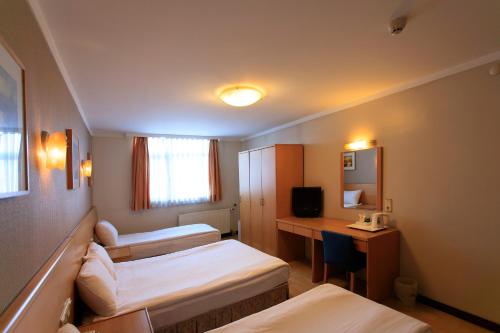 a hotel room with two beds and a desk at Hotel Inter Istanbul in Istanbul